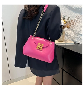 Detail of peach pink chain shoulder bag with gold geometric buckle worn with a blazer