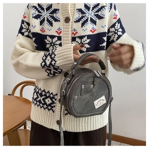 Détail du sac à bandoulière en denim gris avec surpiqûres et écusson de mode