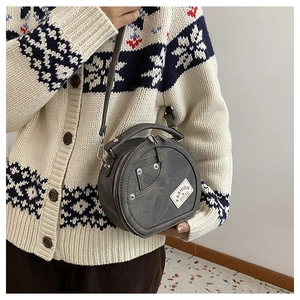 Détail d'un sac bandoulière rond en patchwork de denim avec rivets et étiquette mode