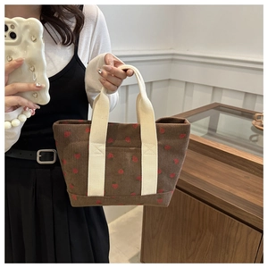 Detailed texture of brown corduroy tote bag with red strawberry embroidery and handles