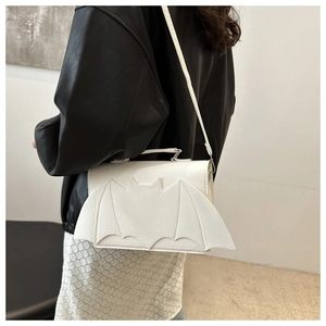 Détail d'un sac à bandoulière blanc avec ailes de chauve-souris et veste en cuir