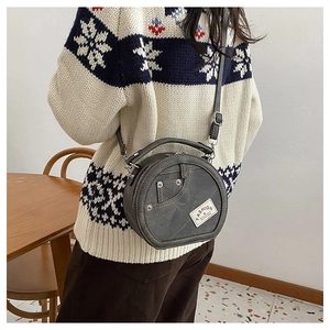 Détail du sac rond en denim avec patchwork, rivets métalliques et étiquette mode