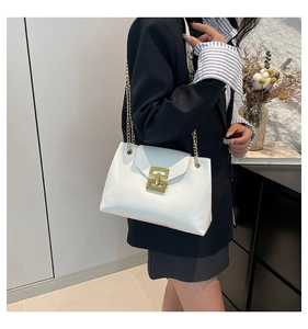Detail of white leather tote with gold square lock and chain strap on a model
