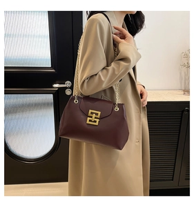 Detail of burgundy leather shoulder bag with gold chain strap and geometric metal lock