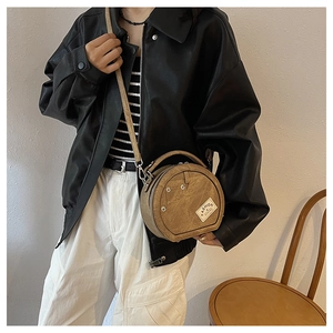 Détail du sac bandoulière rond kaki avec motif poche denim et étiquette fashion