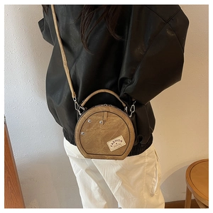 Vue détaillée d'un sac à main rond en patchwork de denim avec rivets métalliques