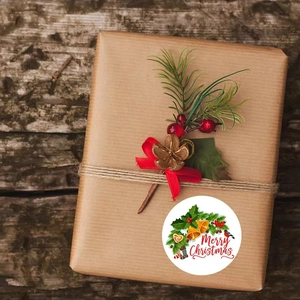 Nahaufnahme eines Merry Christmas Aufklebers auf einer Kraftpapier-Geschenkbox mit Deko