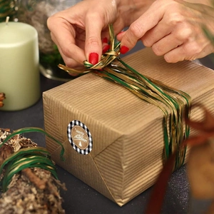 Merry Christmas round stickers on gift box with green silk ribbons and festive ornaments