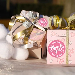 Pink floral thank you stickers on decorative gift box with ribbons and snowballs