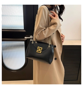Detail of matte black leather handbag with gold geometric buckle on khaki trench coat