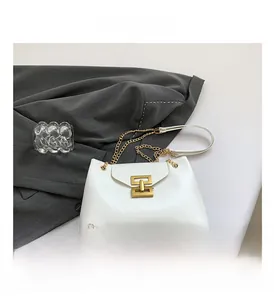 Detail of white glossy chain bag featuring a distinctive gold metal lock and chunky strap