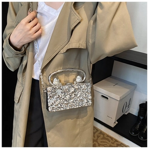Silberne Abend-Clutch mit Eiskristall-Textur und Kettenriemen auf einem khakifarbenen Mantel