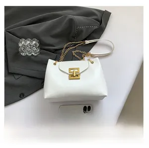 Detail of white leather shoulder bag with gold metal clasp and chain strap on grey blazer