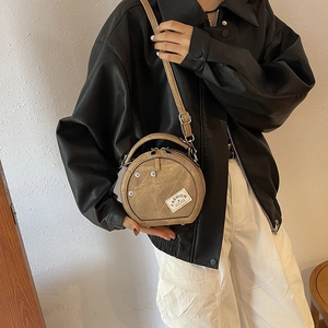 Sac rond bandoulière tendance avec patchwork denim, poignées cuir et rivets