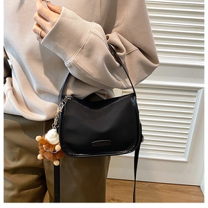 Detail of minimalist black matte handbag with a cute brown plush bear keychain charm