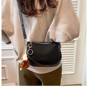 Close-up of black nylon crescent bag with silver zipper and brown plush charm