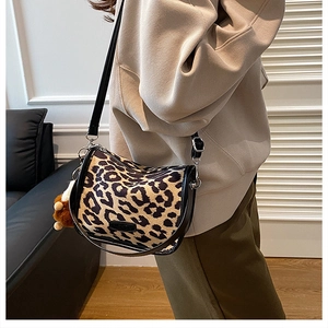 Detail of leopard print pillow bag with black leather trim and plush bear charm
