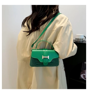 Close-up of green crocodile embossed crossbody bag paired with a beige trench coat
