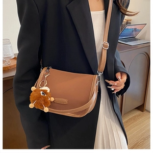 Close-up of brown matte leopard pillow bag with Fashion tag and plush monster charm