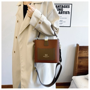 Brown leather bucket bag with olive green pocket worn with a beige trench coat