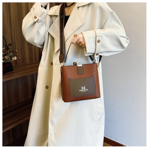 Detail of a brown bucket bag with lychee texture leather and a wide fabric shoulder strap