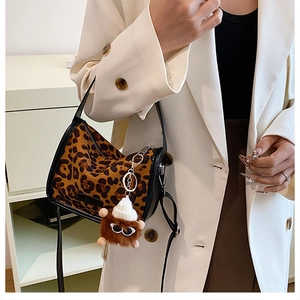 Detail of leopard print cylinder bag with black leather trim and cute plush monster charm