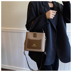 Detail of premium bicolor bucket bag with brand logo and adjustable leather shoulder strap