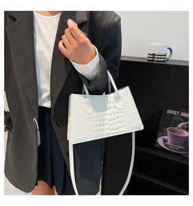 Detail of white crocodile pattern handbag with dual handles and slim shoulder strap