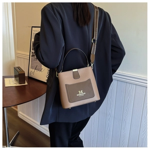 Detail of premium bucket bag with contrast leather pocket and branded wide shoulder strap