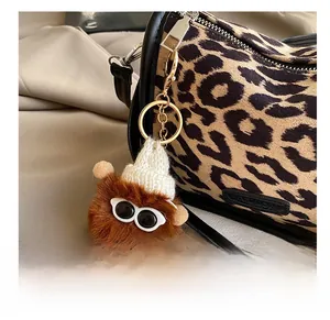 Detail of fluffy brown plush bag charm wearing a white knit hat and small glasses