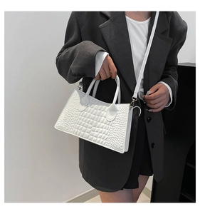 Detailed close-up of white crocodile pattern texture and gold metal hardware on the handbag