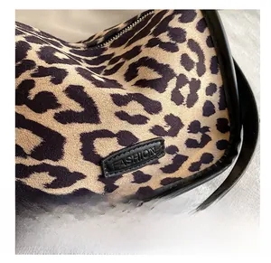 Close-up of leopard print shoulder bag with black leather logo and silver zipper detail