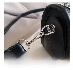 Macro shot of durable silver metal hook and stitching on black matte leather bag
