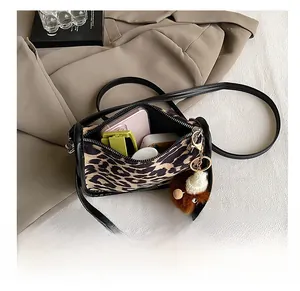Detailed interior of leopard print crossbody bag with items and plush charm