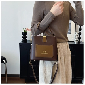 Detail of a retro brown bucket bag with wide shoulder strap in a cozy home setting