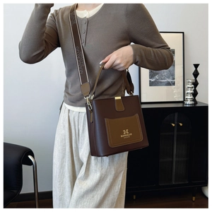 Detail of premium brown bucket bag featuring wide branded strap and pebble leather texture