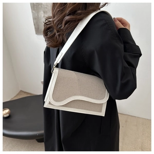 Detail of stylish color-block crossbody bag with canvas and leather wave pattern design