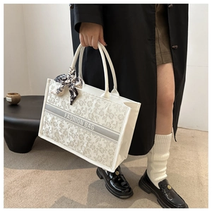 Detail view of large white floral embroidered tote bag with a decorative silk scarf