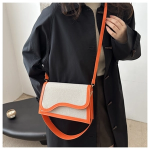 Fashionable PU and canvas crossbody bag with orange leather trim and wavy flap design