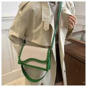 Model wearing stylish cream canvas crossbody bag with green contrast flap and wide strap