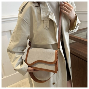 Detail of contrast stitch shoulder bag with cream canvas and brown leather trim
