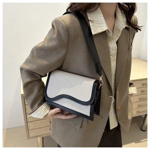Detail of minimalist woven canvas shoulder bag with wave-cut flap and wide leather strap