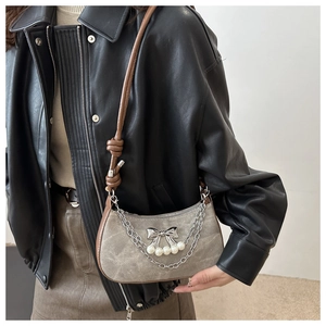 Detail of grey suede hobo bag with pearl bow charms and brown leather strap