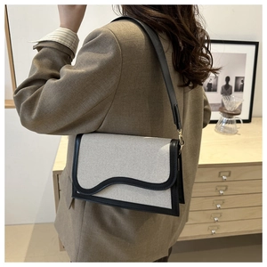 Detail of a chic two-tone shoulder bag featuring wavy flap design and canvas texture