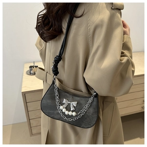 Detail of grey crossbody bag with silver bow and large white pearls on khaki trench coat