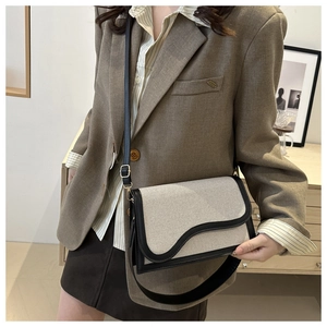 Detail of canvas shoulder bag with black leather wavy flap and dual strap options