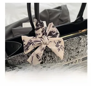 Detailansicht der schwarzen Totebag mit Seidenschal und Vintage-Fabelwesen-Musterung
