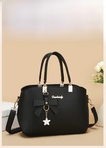 Detail of black pebbled PU tote bag featuring a large bow and star metal pendant