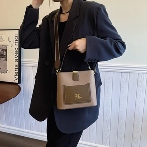 Minimalist large capacity bucket bag with wide woven strap and contrast front pocket