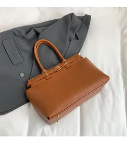 Detail of caramel leather tote bag with gold buckle and bottom protective metal studs